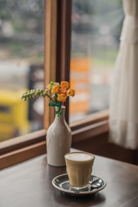 a glass of coffee near a vase